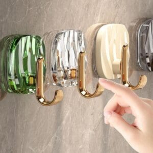 Four colorful wall hooks with golden double hooks mounted on a wall.